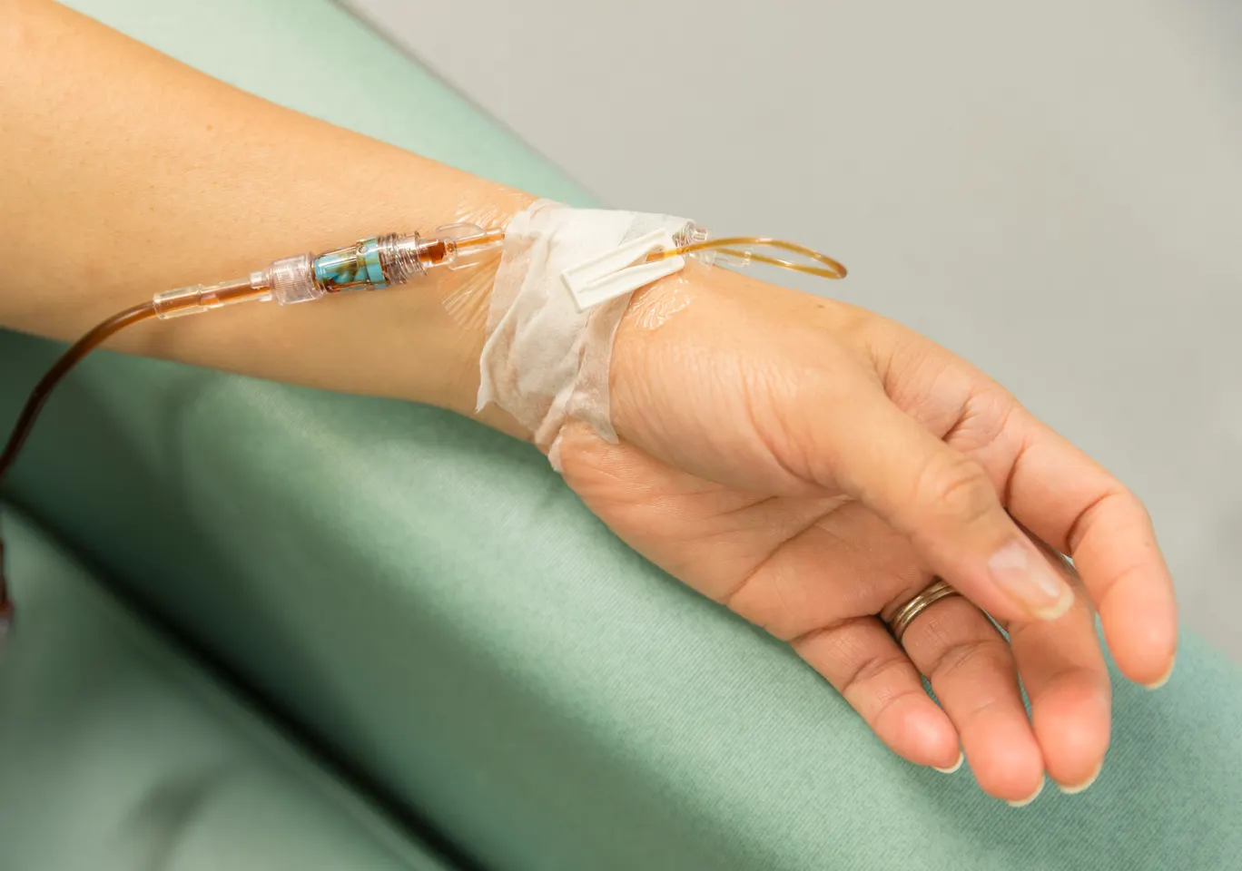 Kroplówki witaminowe Bełchatów: dłoń z wenflonem i linią infuzyjną na podkładzie